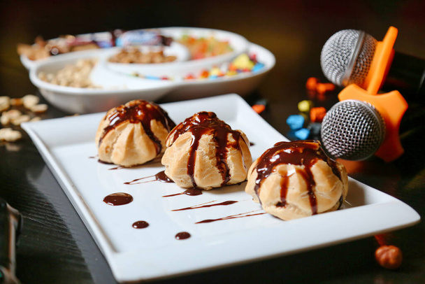Une photo avec trois desserts placés sur une assiette, avec un microphone visible en arrière-plan. - Photo, image