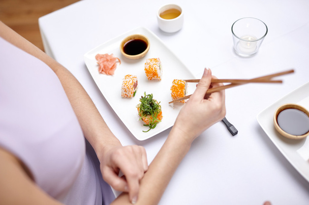 close up of woman eating sushi at restaurant - Foto, afbeelding