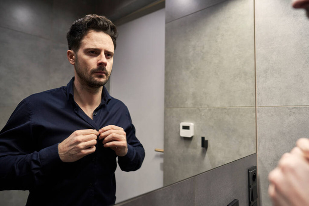 Man draagt casual shirt in de badkamer - Foto, afbeelding