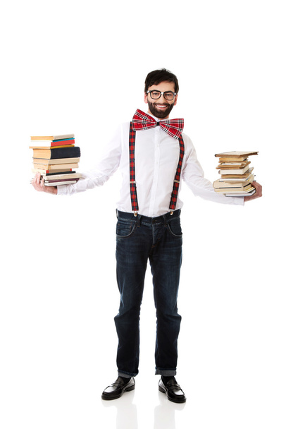 Man wearing suspenders with stack of books. - 写真・画像