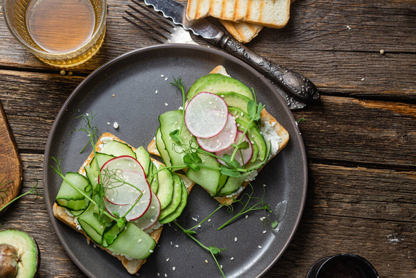 Witte broodjes met roomkaas, avocado, komkommer en radijs in een bord - Foto, afbeelding