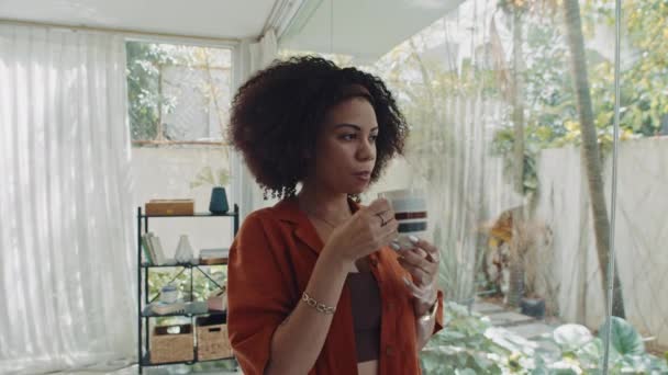 Mediana toma de mujer joven relajada disfrutando de la taza de café de la mañana en el fin de semana en casa - Metraje, vídeo