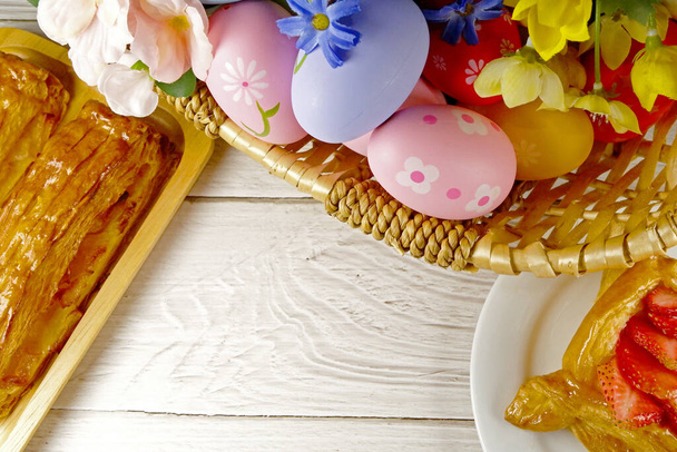 Sepette paskalya yumurtaları ve beyaz arka planda pastalar. Paskalya konsepti - Fotoğraf, Görsel