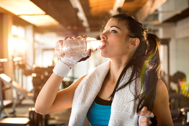 ジムでの運動の若い女性飲料水 - 写真・画像
