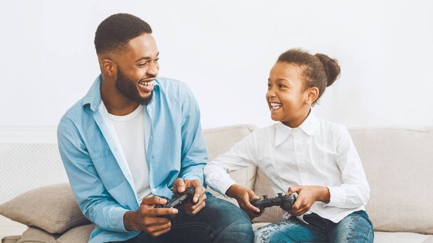 Heureux père et fille jouer à un jeu vidéo, passer du temps ensemble à la maison
 - Photo, image