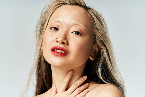 Une femme asiatique captivante aux cheveux longs et au rouge à lèvres frappe une pose. - Photo, image