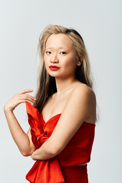 Une jolie femme asiatique dans une robe rouge vibrante frappant une pose pour une photo. - Photo, image