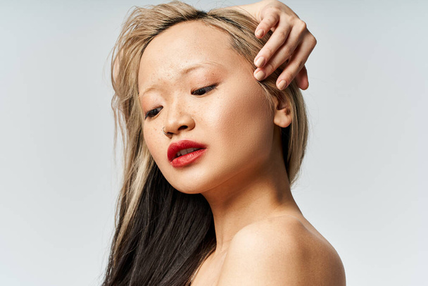 Una atractiva mujer asiática con el pelo largo y lápiz labial rojo golpea una pose en ropa vibrante. - Foto, imagen