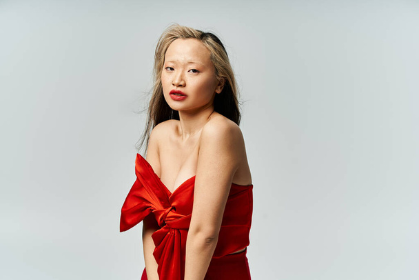 Eine attraktive Asiatin in einem leuchtend roten Kleid posiert für ein Foto. - Foto, Bild