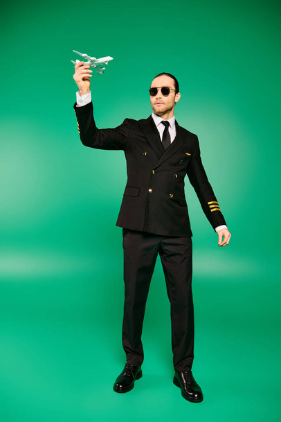 Uomo elegante in giacca e cravatta e occhiali da sole, con in mano un modello di aereo. - Foto, immagini