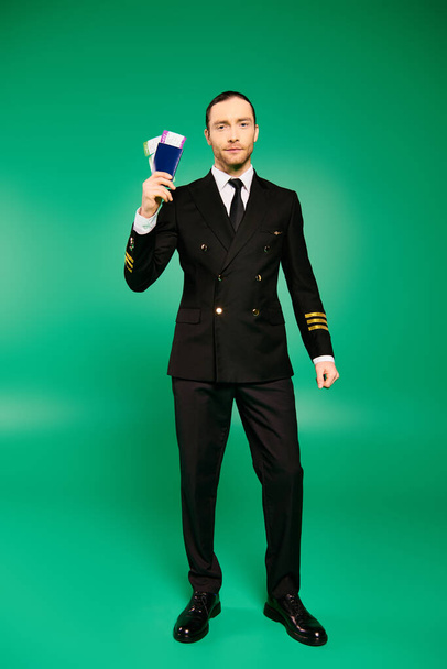 Handsome pilot in black suit holding a passport. - Photo, Image