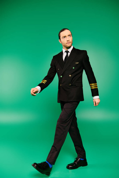 Κομψός άντρας με κοστούμι και γραβάτα περπατά με χάρη σε ένα καταπράσινο φόντο. - Φωτογραφία, εικόνα