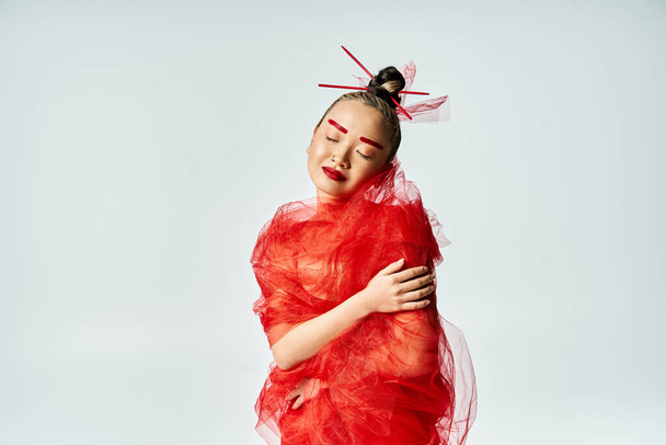 Egy élénk ázsiai nő piros ruhában fátyolba burkolózik.. - Fotó, kép
