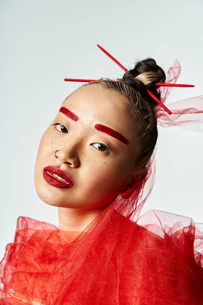 Asian woman in red dress poses with sticks sticking out of her face. - Photo, Image