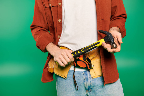 Handsome male worker in uniform posing with hammer on green backdrop. - Photo, Image
