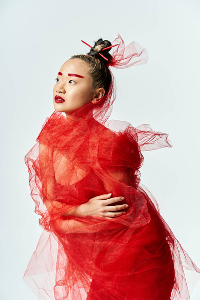 Elbűvölő ázsiai nő kecsesen pózol élénk piros ruhában és fátyolban.. - Fotó, kép