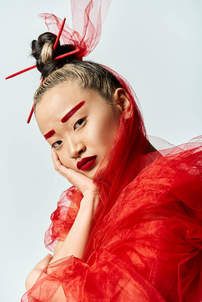 Eine bezaubernde Asiatin in roter Kleidung und Make-up nimmt eine dynamische Pose ein. - Foto, Bild
