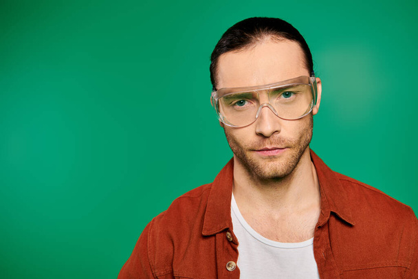 Handsome male worker in uniform and glasses, posing with tools on a vibrant green background. - Photo, Image