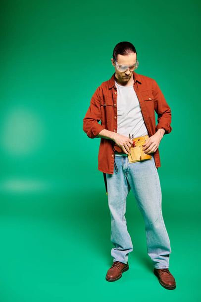 Komea mies univormussa, poseeraa työkalujen kanssa elinvoimaisella vihreällä taustalla. - Valokuva, kuva