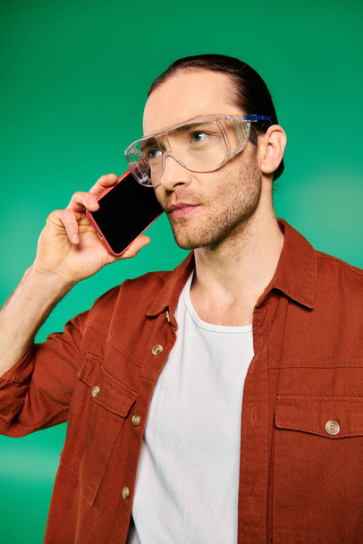 Een man met een bril in gesprek op zijn mobiele telefoon. - Foto, afbeelding