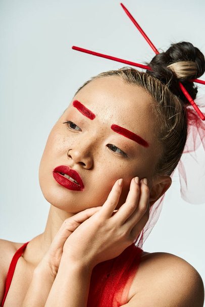 Une femme asiatique captivante ornée d'un maquillage rouge et d'un voile fluide. - Photo, image