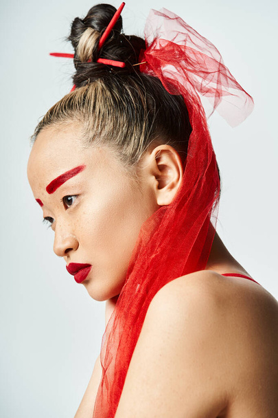 Привлекательная азиатка с яркими рыжими волосами и интенсивным красным макияжем уверенно позирует. - Фото, изображение