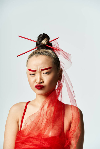 活気に満ちたアジアの女性は彼女の頭にヴェールが付いている赤いドレスでポーズします. - 写真・画像