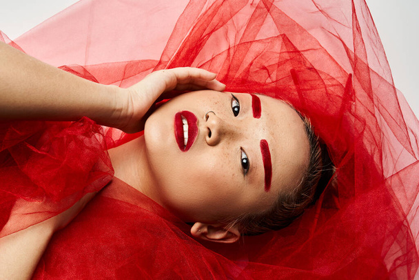 Яскрава азіатська жінка позує в яскравій червоній сукні і відповідний макіяж. - Фото, зображення