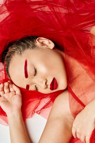 Μια ελκυστική Ασιάτισσα με ζωηρά ρούχα και κόκκινο κραγιόν ξαπλωμένη σε ένα κρεβάτι. - Φωτογραφία, εικόνα