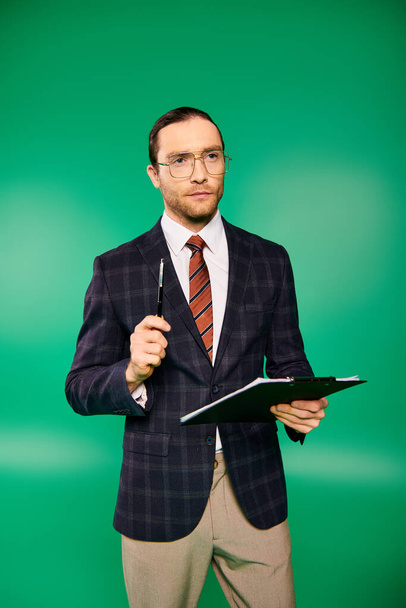 Schöner Geschäftsmann im schicken Anzug mit Klemmbrett auf grünem Hintergrund. - Foto, Bild