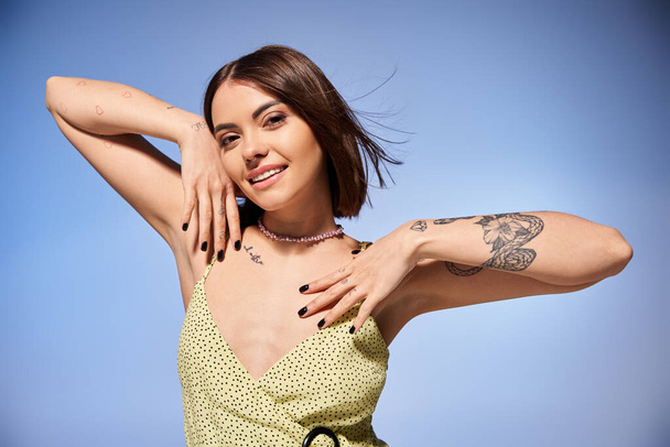 Een jonge vrouw met brunette haar poseert vol vertrouwen voor een foto, presentatie van een opvallende tatoeage op haar arm. - Foto, afbeelding