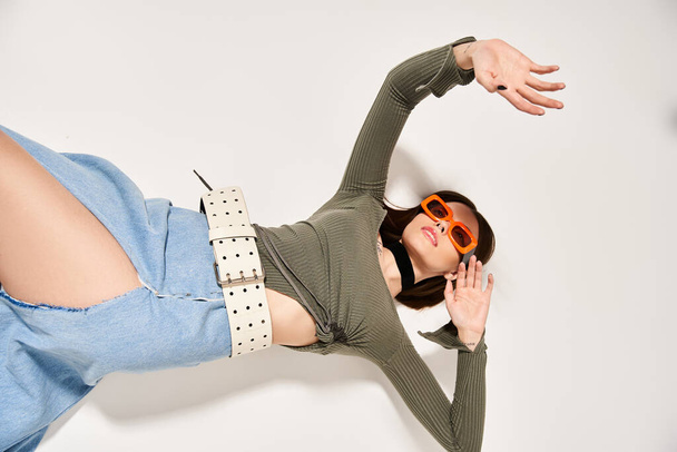 A young woman with brunette hair wearing sunglasses and a green shirt in a studio setting. - Photo, Image