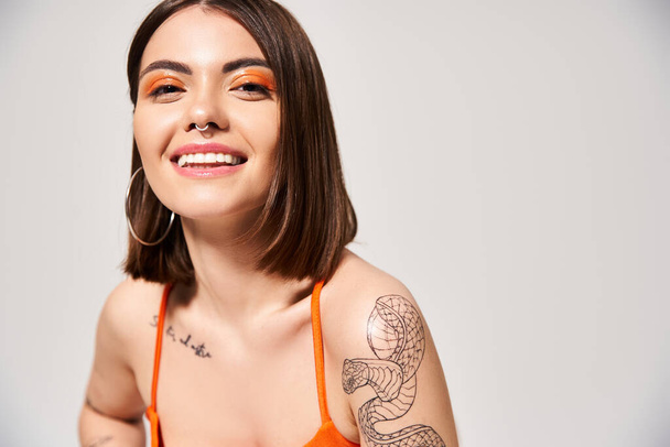 Стильна молода жінка з брюнеткою, що демонструє красиве татуювання на руці в студійній обстановці. - Фото, зображення