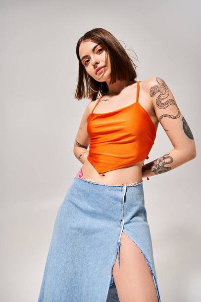 A young woman with brunette hair dancing gracefully in a vibrant orange top and a flowing blue skirt. - Photo, Image
