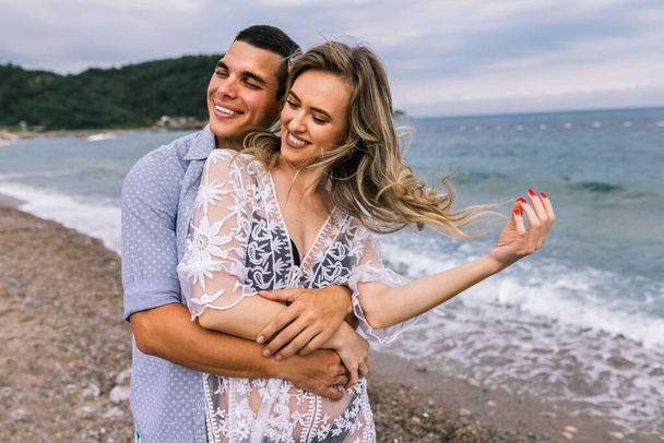 Onnellinen nuori pari nauraa ja halaa rannalla - Valokuva, kuva