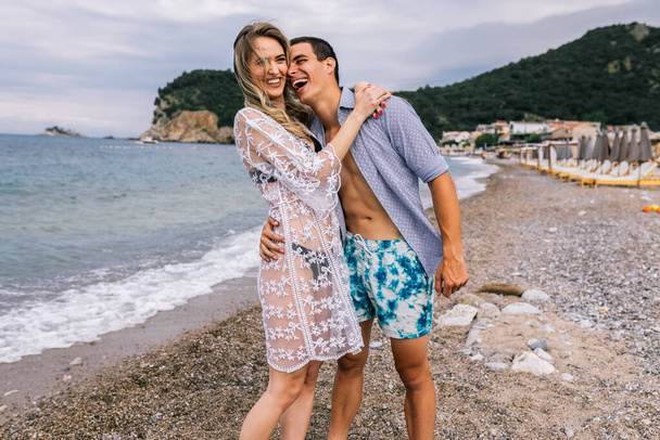 Boldog fiatal pár nevet és ölelkezik a parton - Fotó, kép