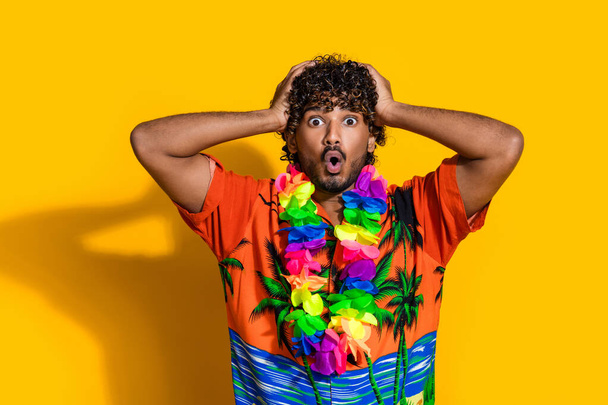 Photo of speechless man dressed print shirt flower necklace staring at sale holding arms on head isolated on yellow color background. - Φωτογραφία, εικόνα