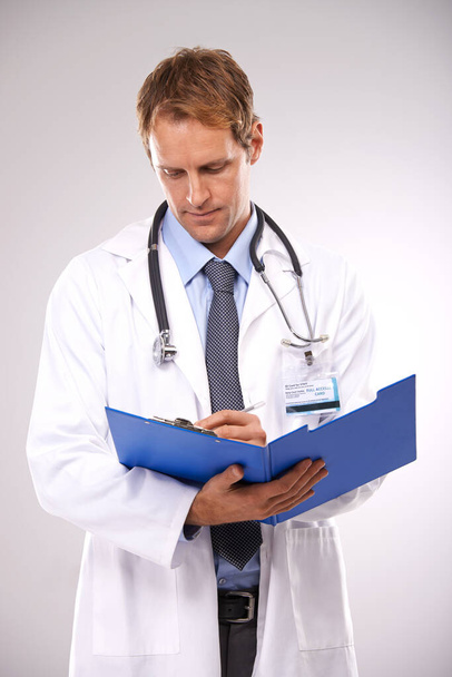 Clipboard, writing and doctor in studio for medical report, insurance and research for hospital. Healthcare, clinic and worker with documents for consulting, wellness and planning on gray background. - Photo, Image