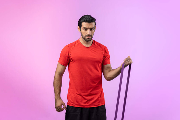 Full body length gaiety shot athletic and sporty young man with fitness elastic resistance band in standing posture on isolated background. Healthy active and body care lifestyle. - Photo, Image