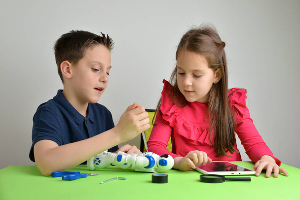 Kinder bauen Roboter auf dem Arbeitstisch zusammen und unterhalten sich. Konzept von Teamarbeit, Zusammenarbeit, Bildung und praktischer Lernerfahrung - Foto, Bild