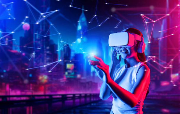 Smart female standing in cyberpunk style building in meta wear VR headset connecting metaverse, future cyberspace community technology, Woman use index fingers touching virtual object. Hallucination. - Photo, Image
