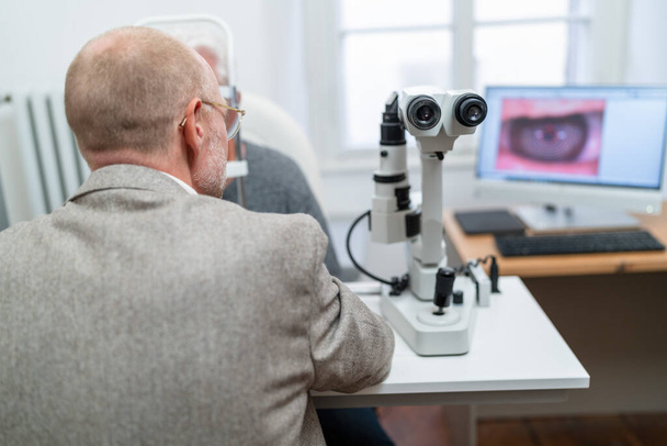 Augenoptiker beim Blick durch den Keratographen während einer Augenuntersuchung in der Augenklinik. Nahaufnahme. Gesundheits- und Medizinkonzept - Foto, Bild