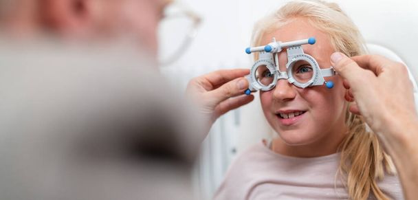 Νεαρή κοπέλα να πάρει την όρασή της ελεγχθεί με οπτικά γυαλιά μέτρησης από έναν οφθαλμίατρο. - Φωτογραφία, εικόνα