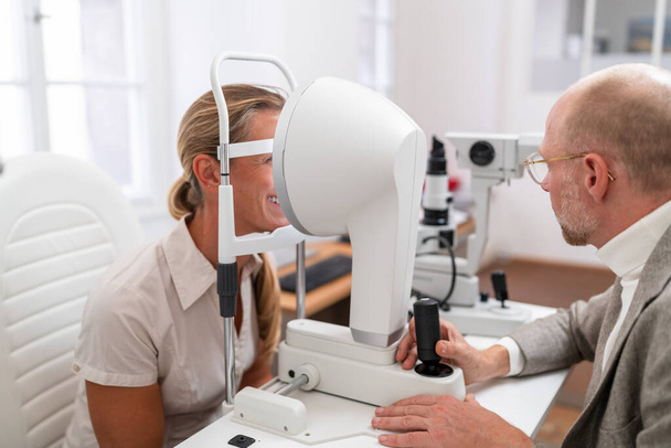 Optometrist die Keratograph gebruikt voor een oogtest bij een vrouwelijke patiënt in de oogheelkundige kliniek. Een close-up foto. Begrip gezondheidszorg en geneeskunde - Foto, afbeelding