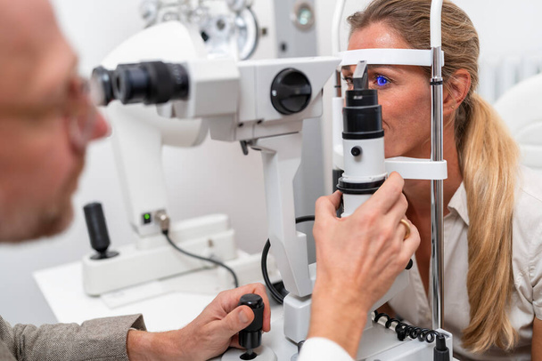 Primer plano de un examen ocular con un optometrista ajustando la lámpara de hendidura en la clínica de oftalmología. Fotografía de cerca. Concepto de salud y medicina - Foto, imagen