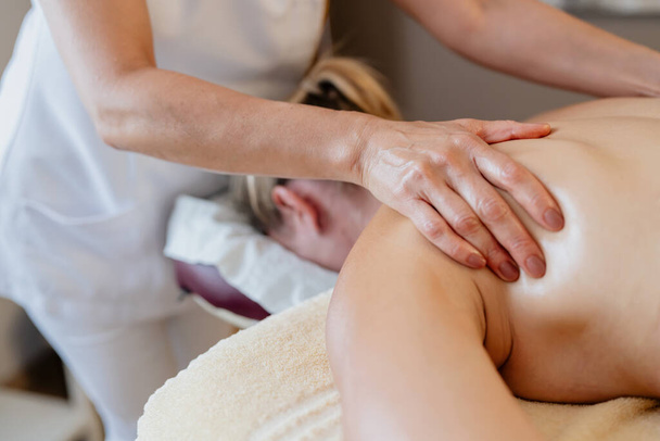 Close-up de um terapeuta de massagem trabalhando no ombro de um cliente em um salão de beleza spa Wellness Hotel Imagem conceito - Foto, Imagem