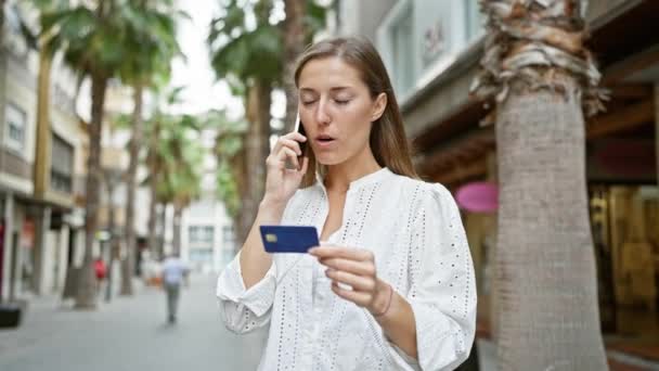 Egy fiatal nő, akinek hitelkártyája van, és telefonon beszél a városban. - Felvétel, videó