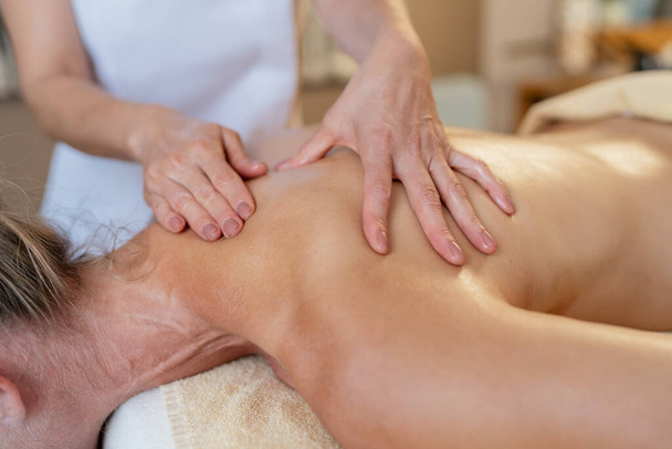 Visão de perto de um massagista aplicando pressão nas costas de uma cliente feminina - Foto, Imagem
