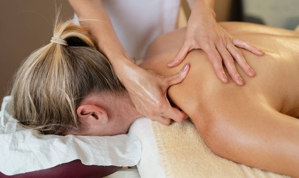 Masážní terapeut aplikující masáž ramen a zad na náchylnou ženu. beauty salon Wellness Hotel Concept image - Fotografie, Obrázek