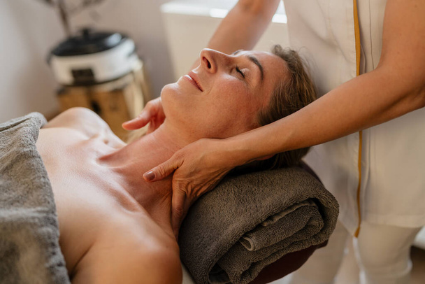 Mulher recebendo uma massagem relaxante no pescoço em um spa com as mãos de um terapeuta em seu ombro. salão de beleza Wellness Hotel Imagem de conceito - Foto, Imagem